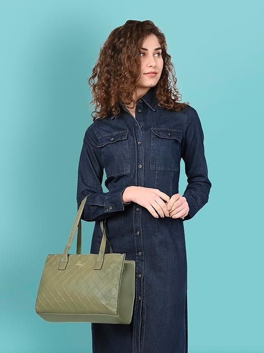 Person in a denim dress holds a quilted handbag, looking to the side against a plain background