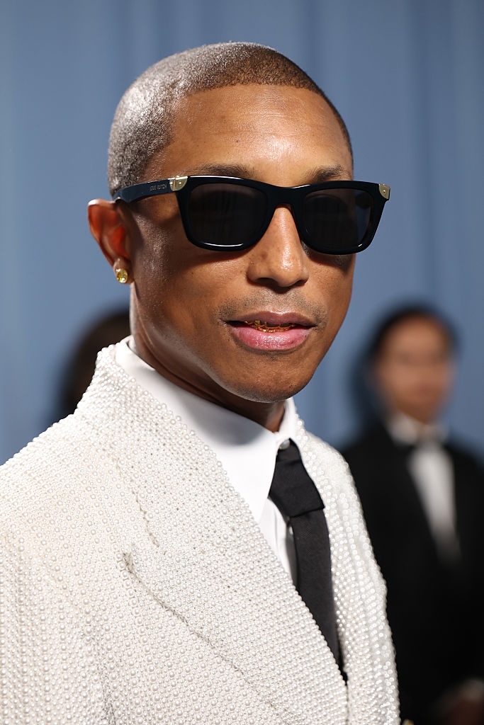 Person in a pearl-encrusted jacket, black tie, and sunglasses on a formal event red carpet