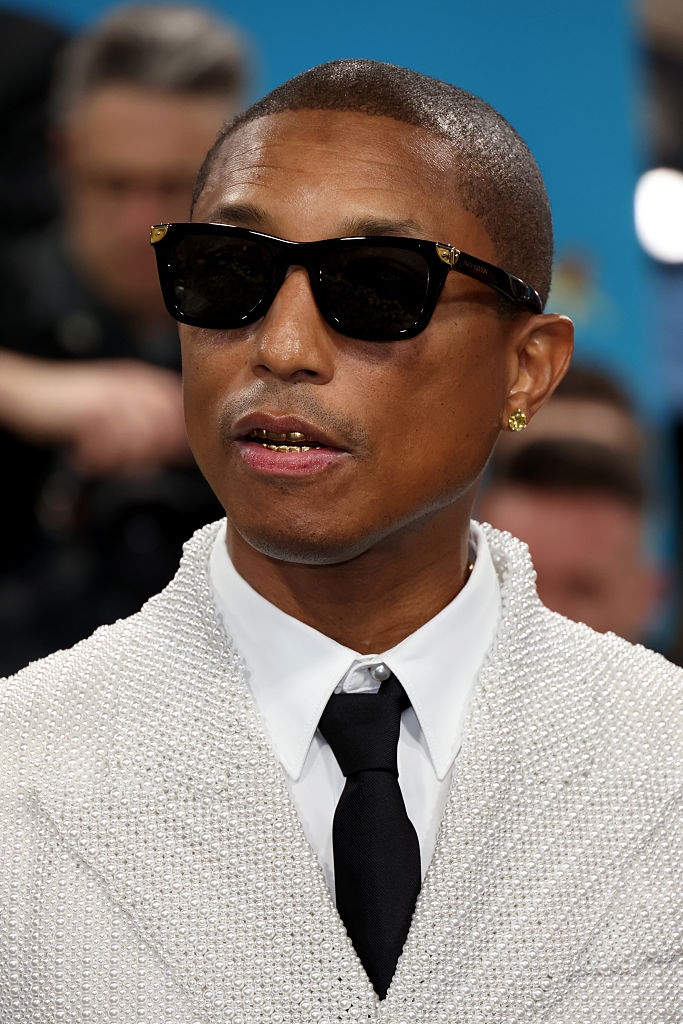 Person wearing sunglasses and a textured suit with a black tie at a formal event