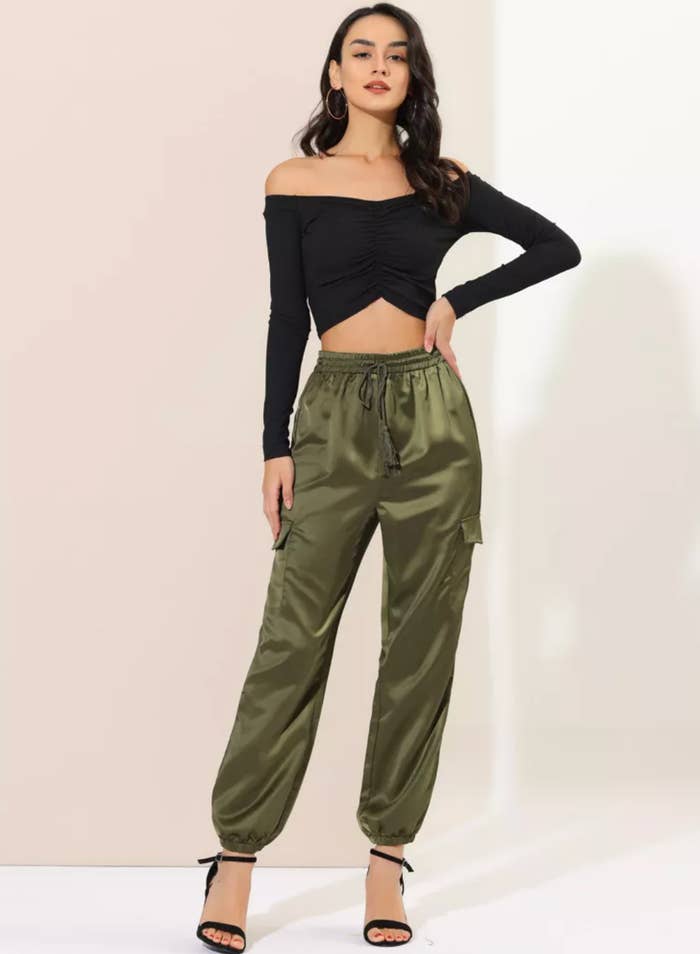 model successful  an off-shoulder apical  and satin joggers poses confidently, wearing precocious   heels