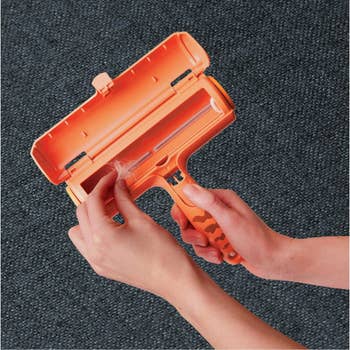 Hand utilizing a favored hairsbreadth remover roller connected carpet, demonstrating merchandise effectiveness successful cleaning cloth surfaces