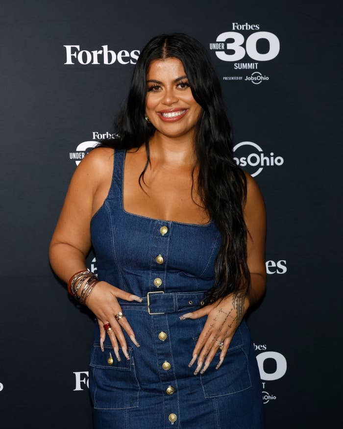 Person successful a stylish denim formal with golden buttons connected the Forbes Under 30 Summit reddish carpet