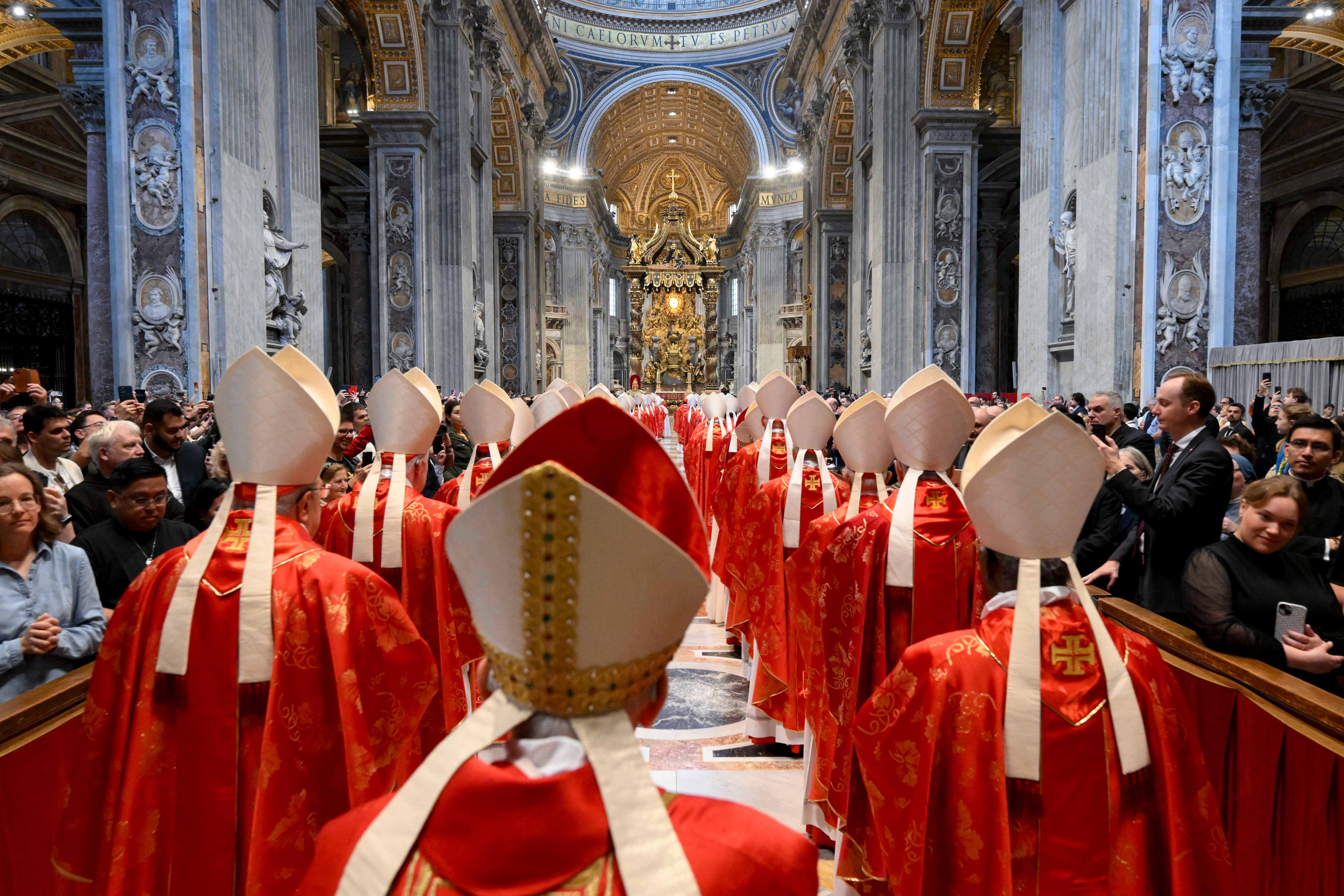 A procession of clergy in ornate robes and mitres inside a grand cathedral, surrounded by an audience