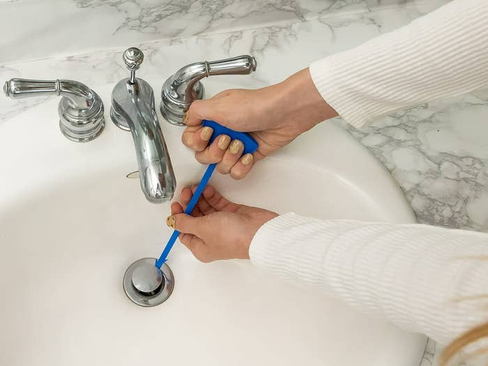Hands utilizing a bluish instrumentality to cleanable a bath descend drain
