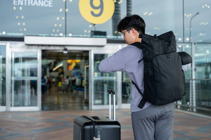 Man standing outside of airport with luggage