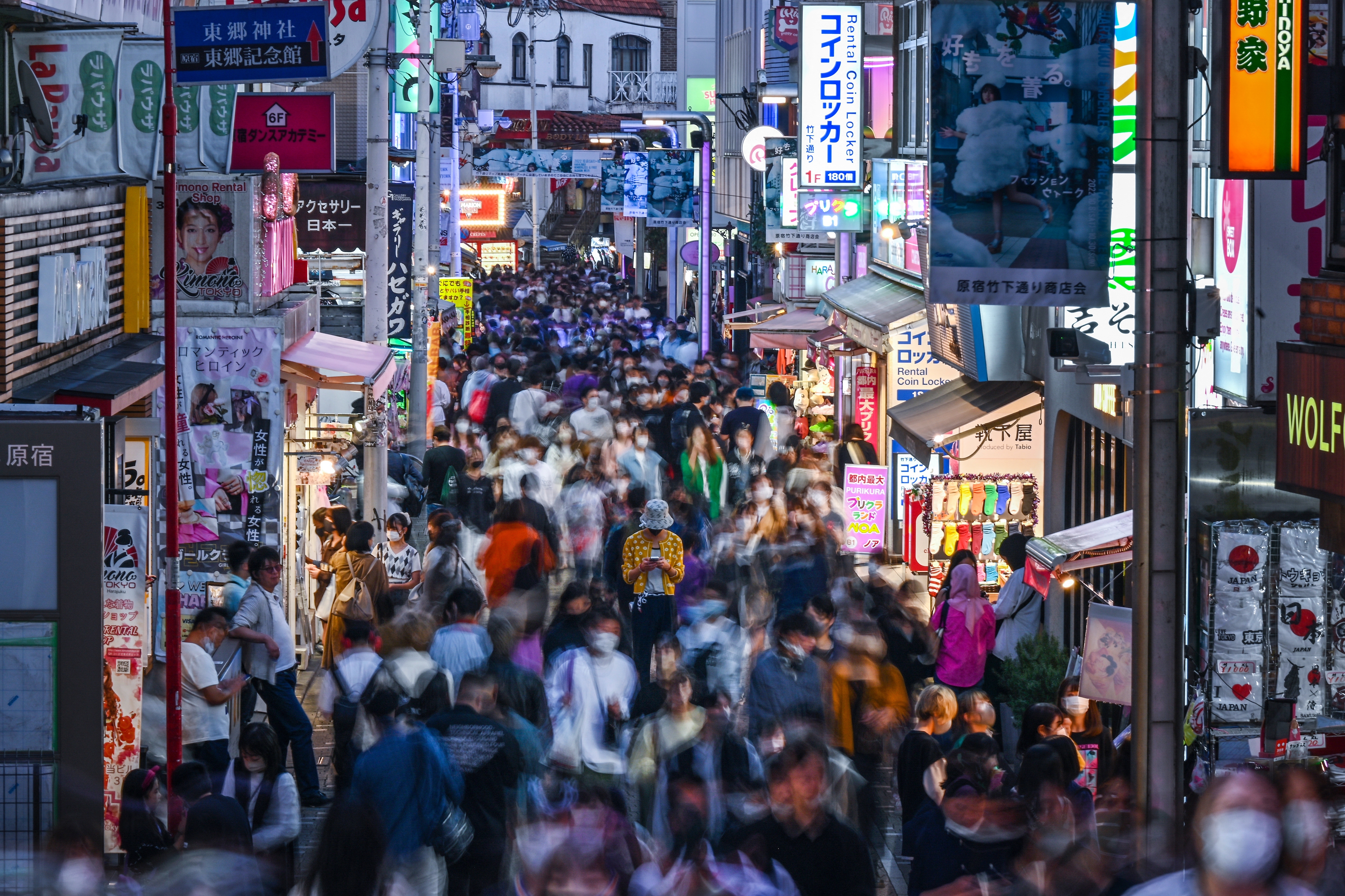 Busy street in Tokyo with crowds of people shopping and walking, surrounded by colorful store signs and vibrant energy