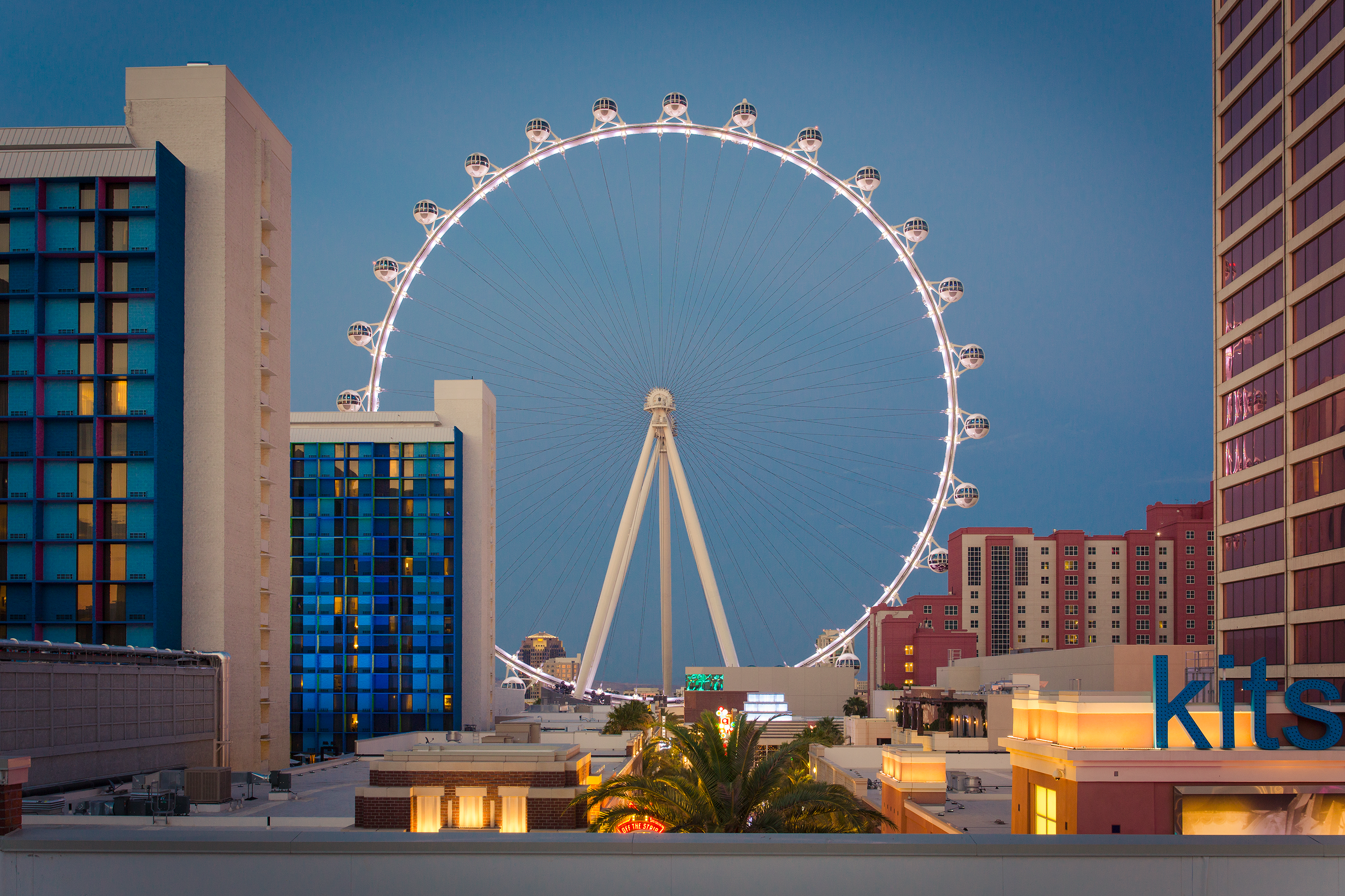 Ferris wheel at night with office buildings in the foreground, creating a contrasting urban skyline