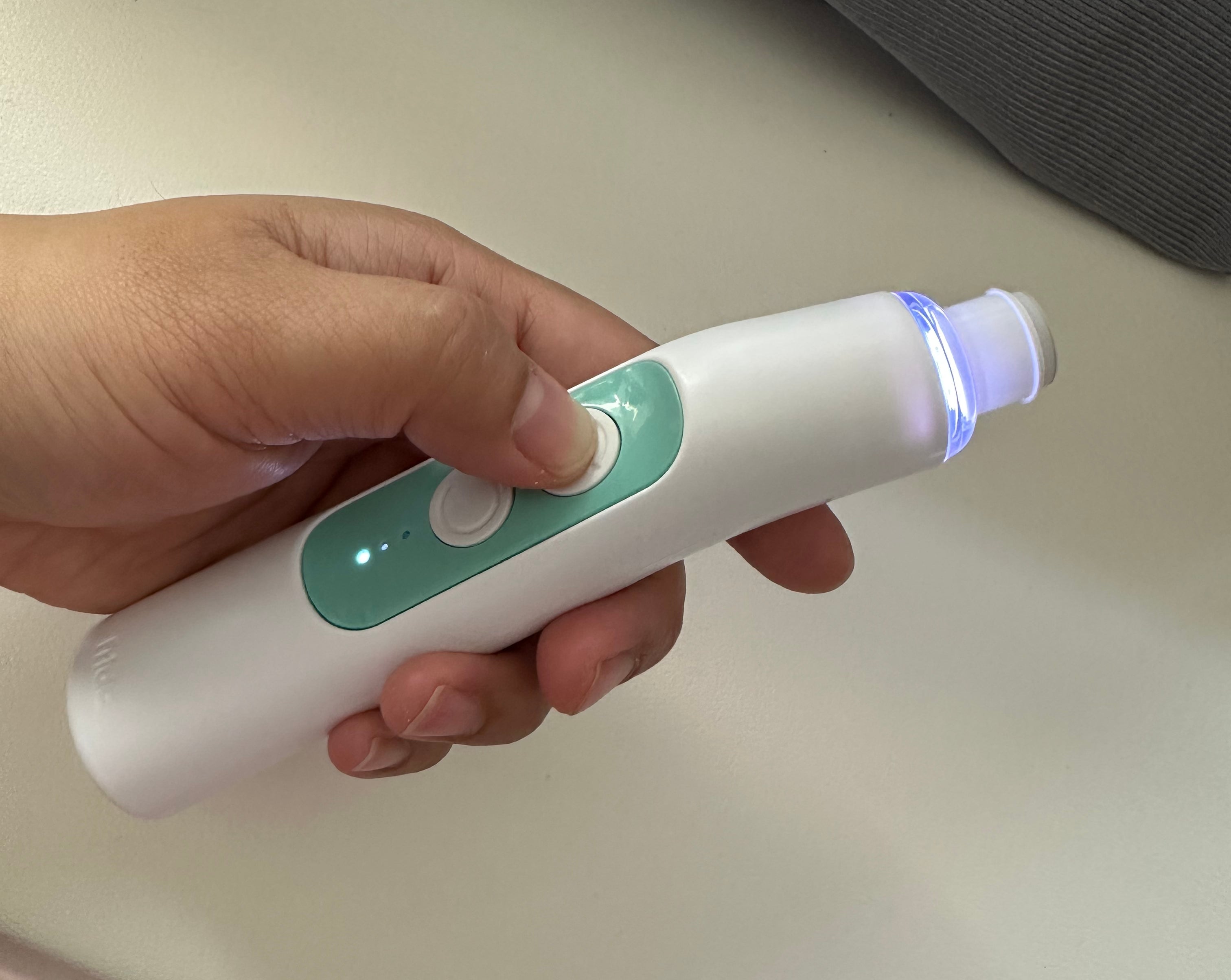 Person holding a handheld electronic device with buttons near a computer keyboard