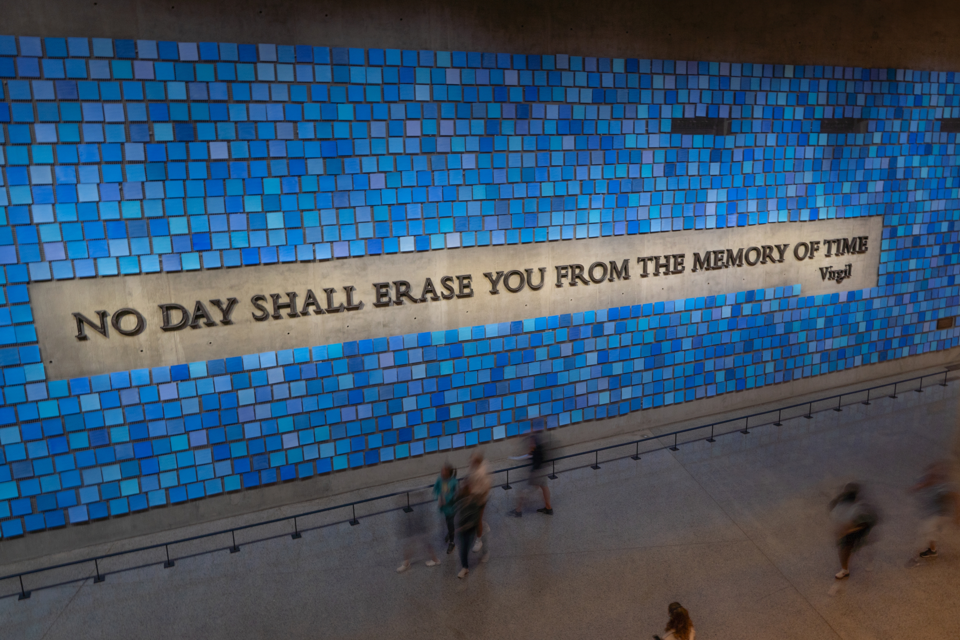 Wall with blue tiles at World Trade Center Memorial, featuring quote: "No day shall erase you from the memory of time" by Virgil