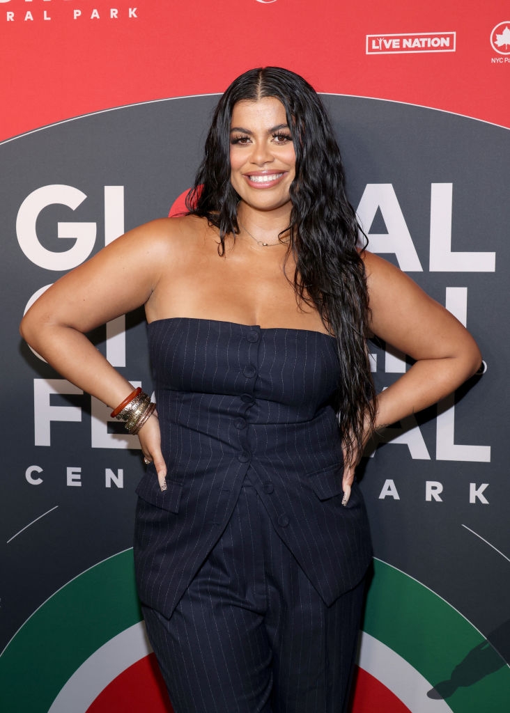 Person posing on the red carpet in a strapless, pinstripe outfit with wavy hair at a celebrity event