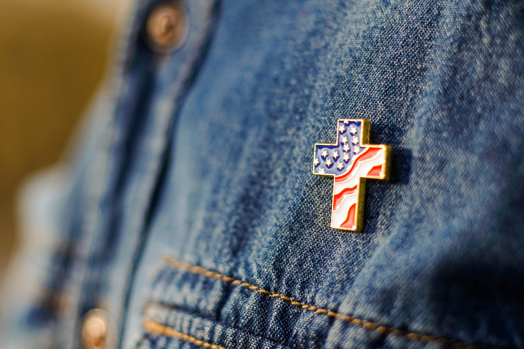 Cross-shaped pin with American flag design on denim jacket