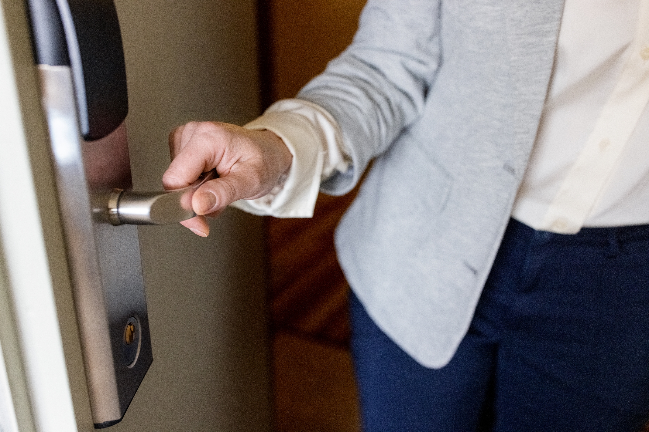 Person in business attire opening a door with a modern handle