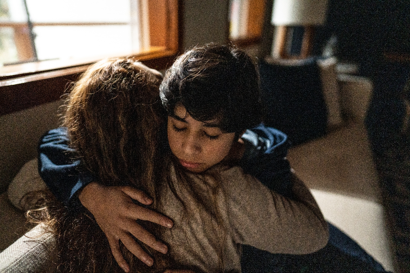 Two people share a comforting embrace in a cozy room, offering a sense of warmth and support