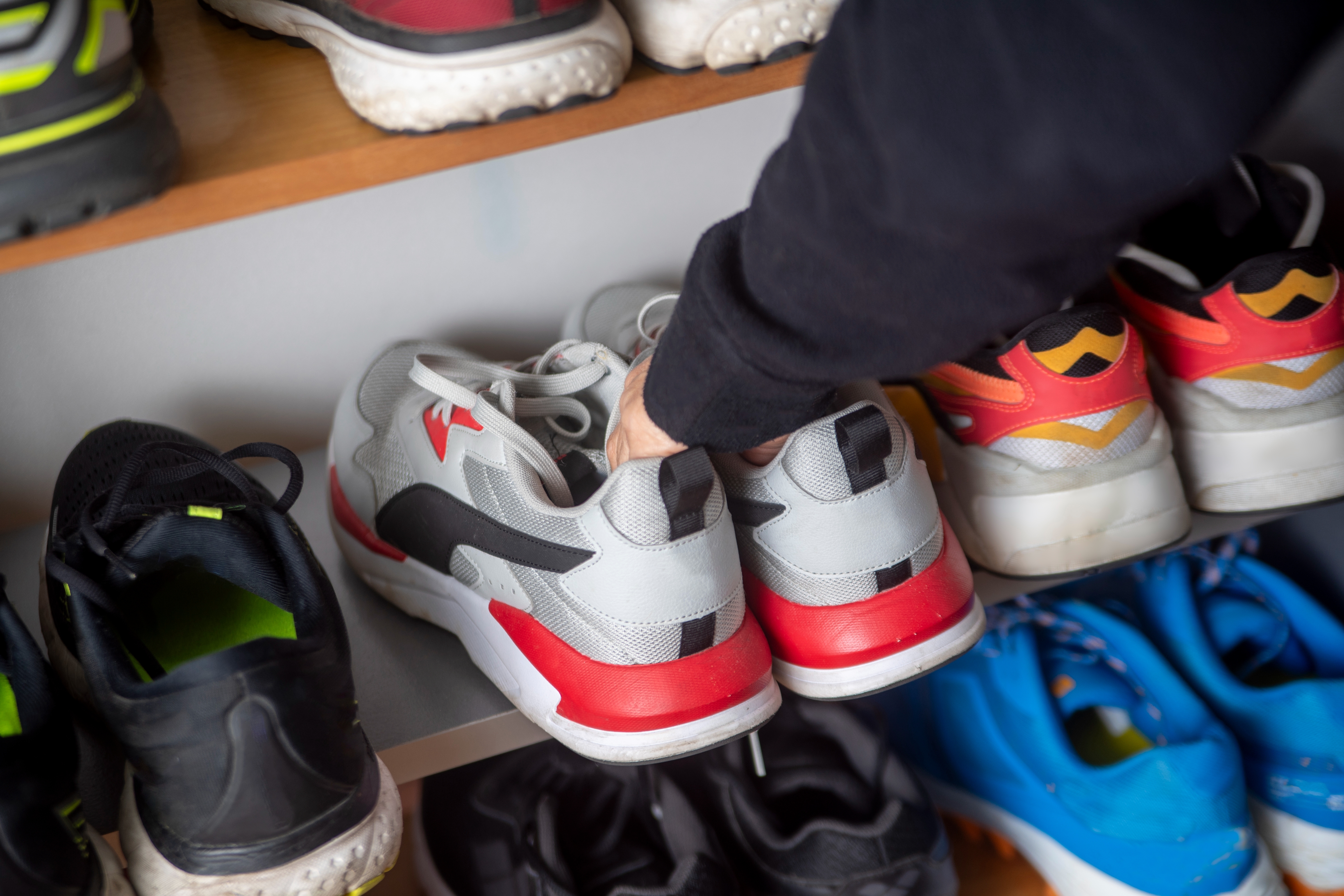 Person organizes shelves filled with various athletic shoes