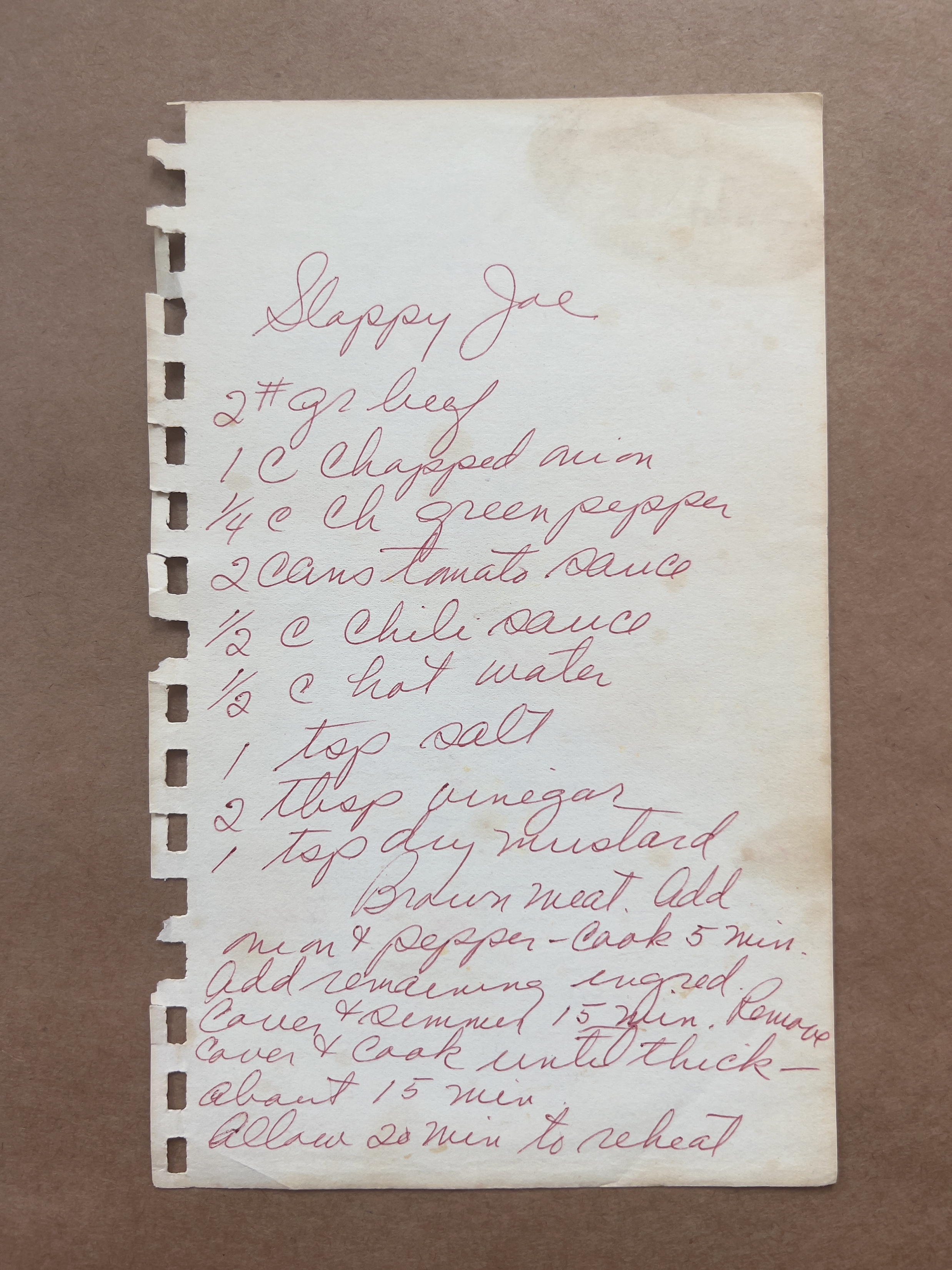 Handwritten Sloppy Joe recipe on lined paper with ingredients and cooking instructions, focusing on ground beef, peppers, and sauce preparation