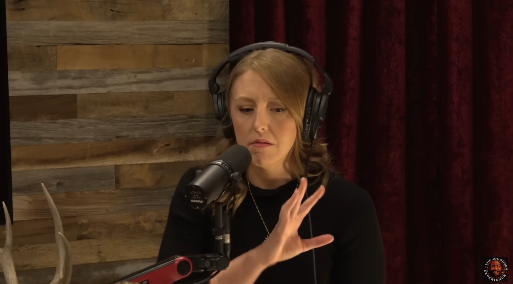 Person speaking into a microphone and wearing headphones in a podcast studio