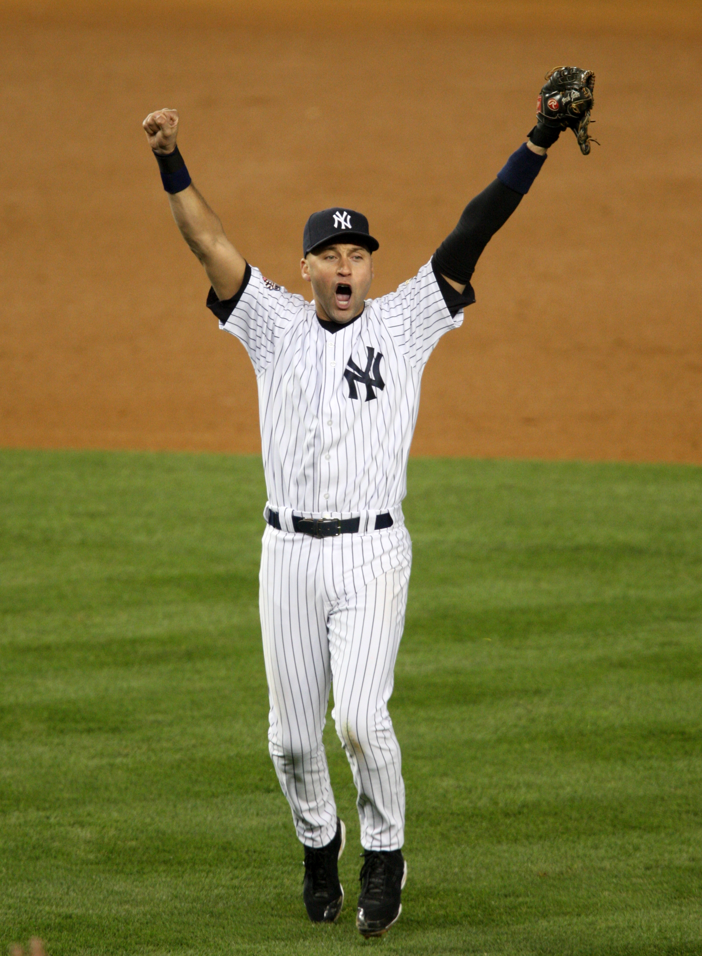 Baseball player in striped uniform celebrates with arms raised on the field