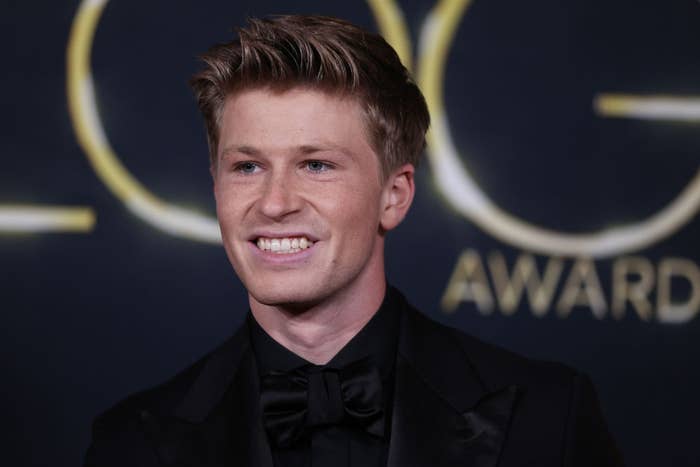 Person wearing a black suit and bow tie at an awards event, smiling for the camera