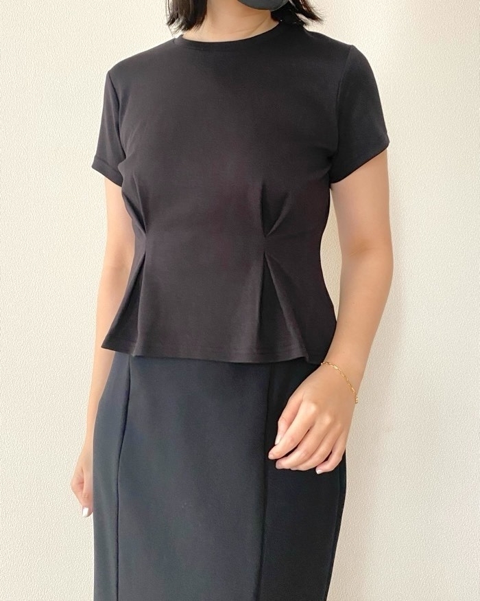女性がシンプルな黒いトップスとスカートを着用しています。