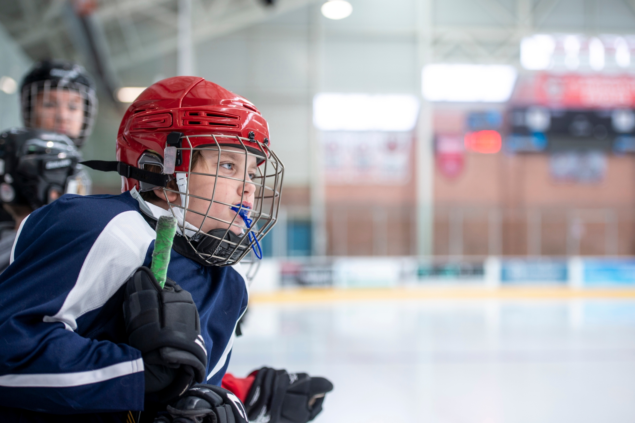 Youth ice hockey player in action, wearing a helmet and a jersey, intensely focused on the game