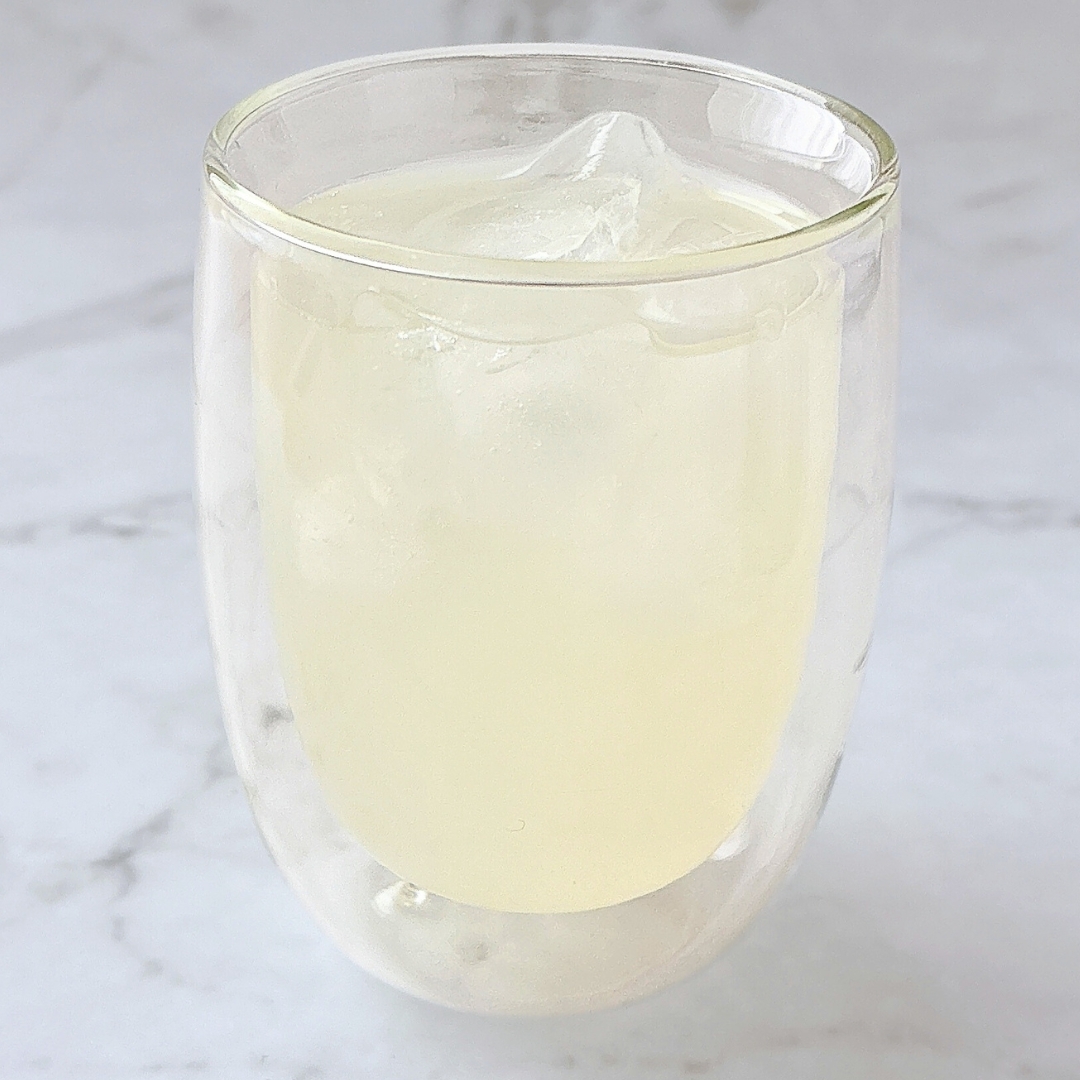 氷入りの透明なグラスに注がれた冷たい飲み物。背景はマーブル風。