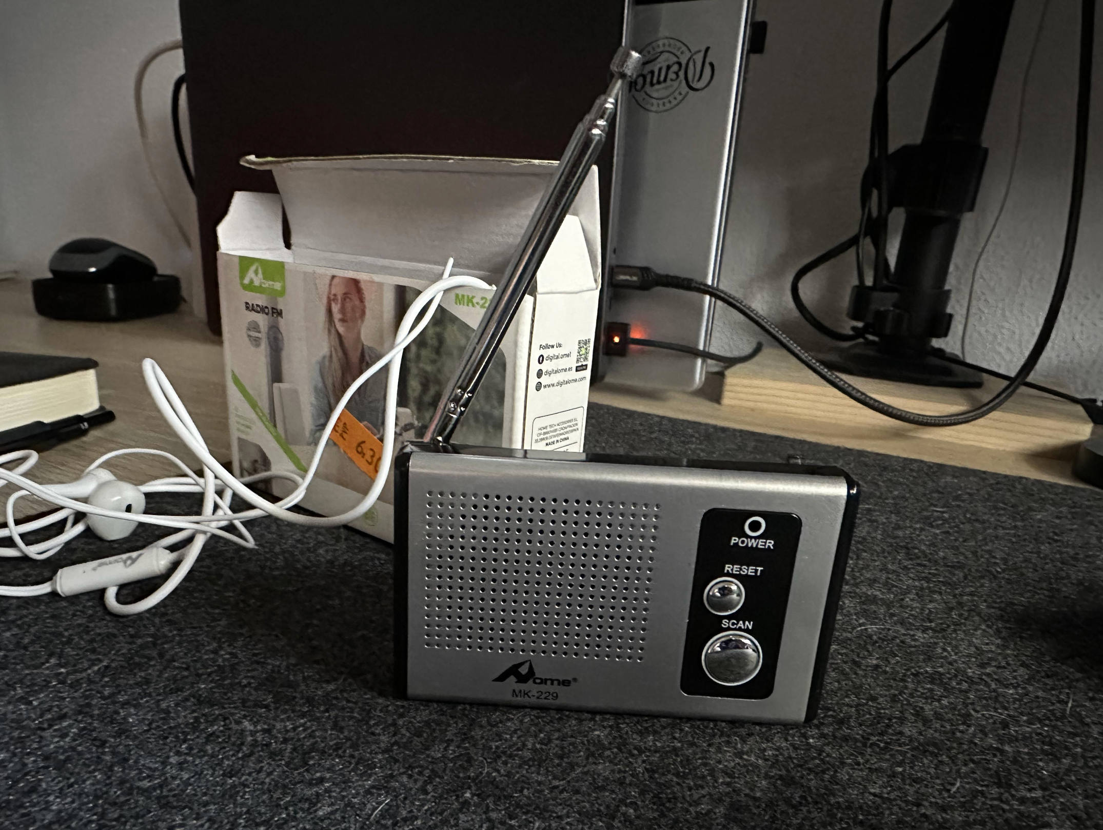 Portable radio with earphones next to a partially opened box on a desk