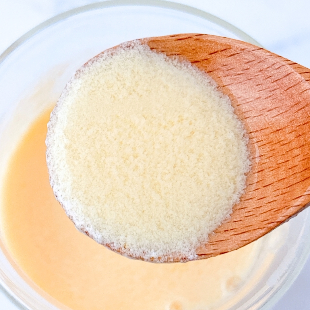 木のスプーンに載せた粉末のクローズアップ。下には液体が見える。