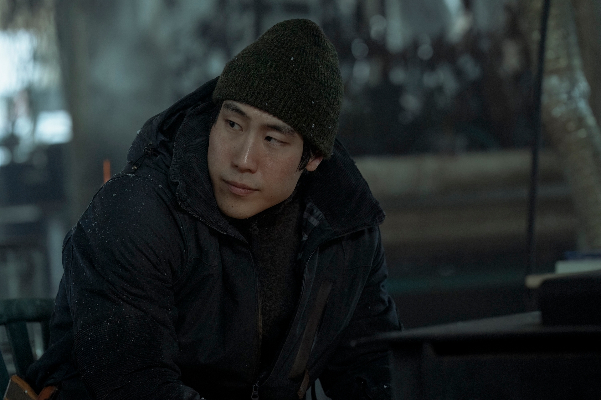 Persona mirando pensativa a la derecha, vestida con abrigo grueso y gorro de invierno en un entorno frío