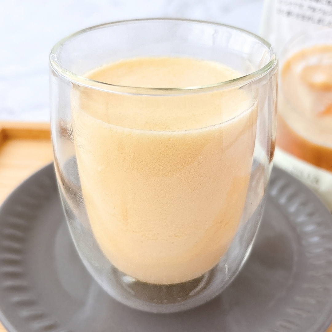 透明のガラスカップに注がれたクリーミーなコーヒーが灰色の皿に載せられている。