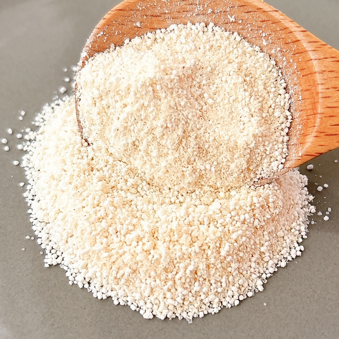 木製スプーンからこぼれ落ちる粉末の近接画像。