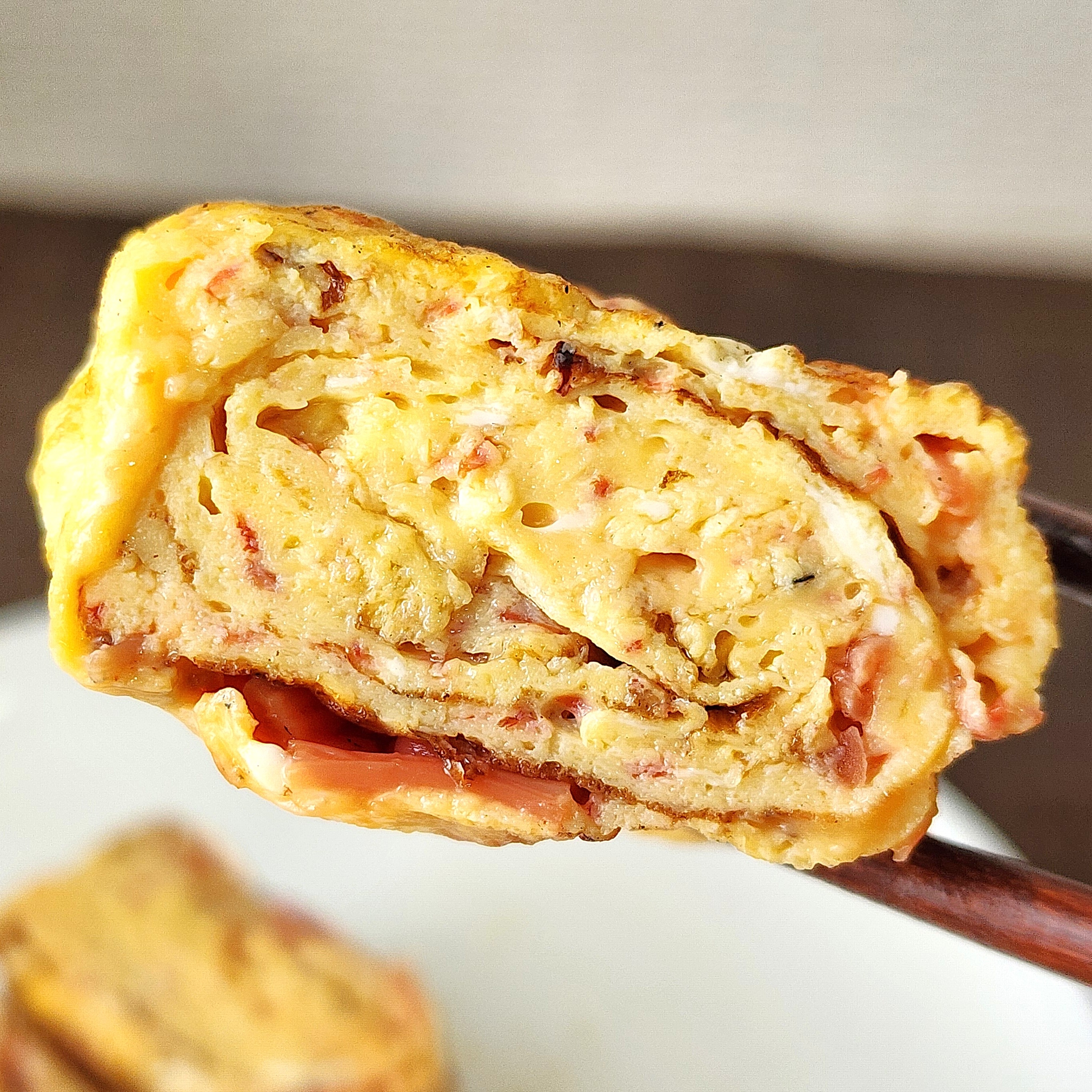 卵焼きが箸で持ち上げられている様子。巻かれた層が見えている。