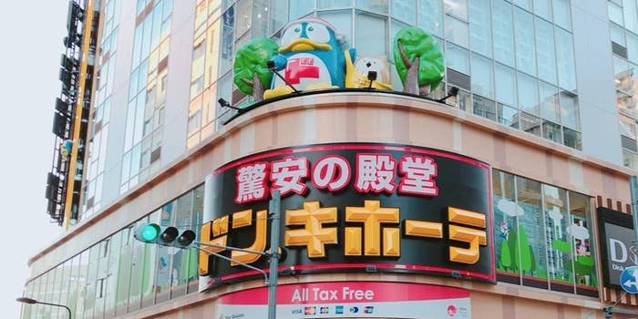 ドン・キホーテの広告があるビルの外観で、建物の上にはペンギンと犬のマスコットが飾られています。