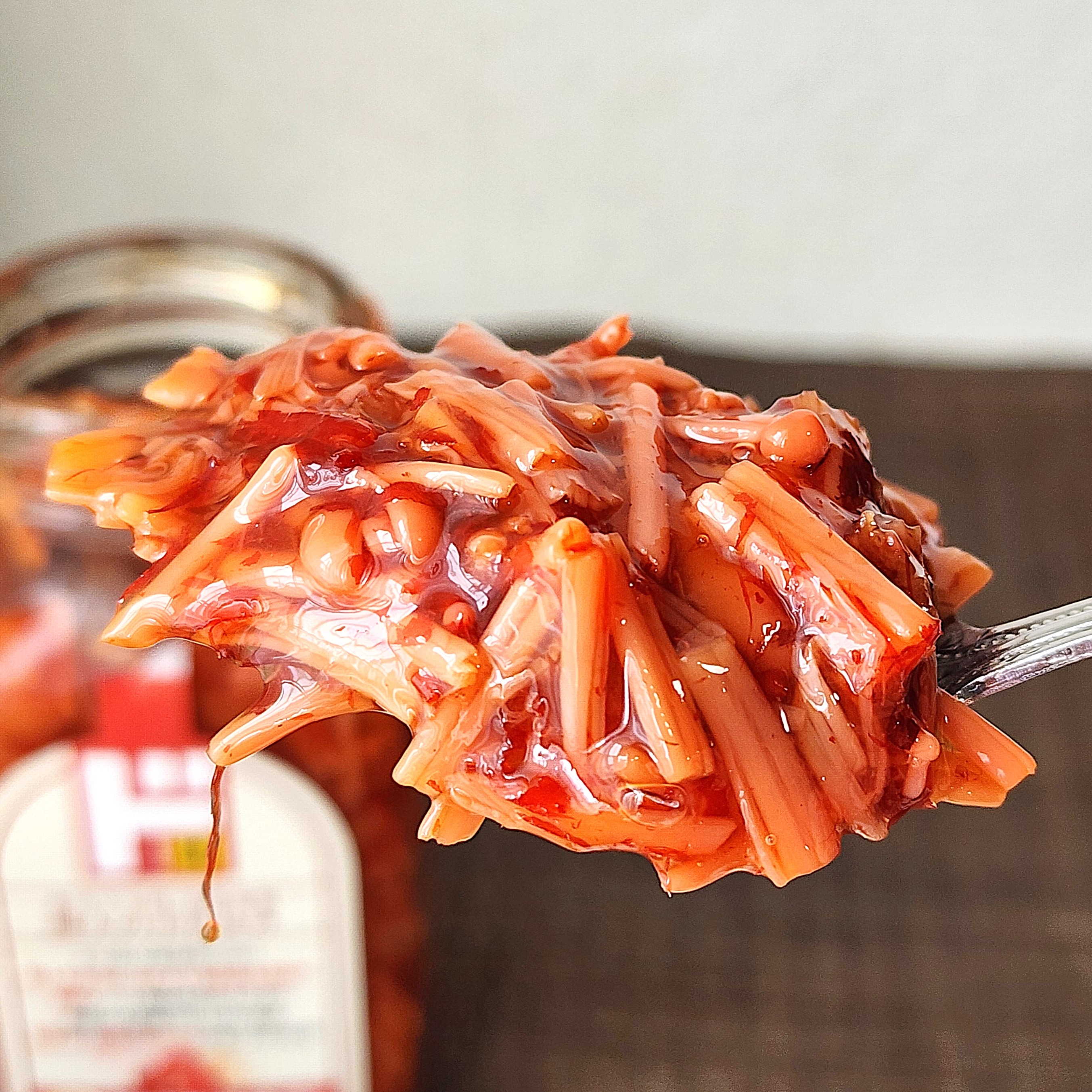 瓶詰めの発酵キノコ料理がスプーンに盛られている様子。