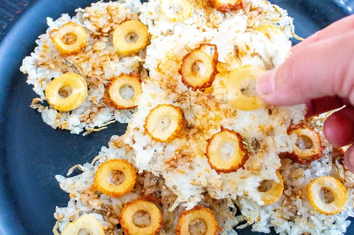 手で持って食べられる、丸い具材が乗ったご飯の料理。黒い皿に盛られた、一口サイズの伝統的なスナック。