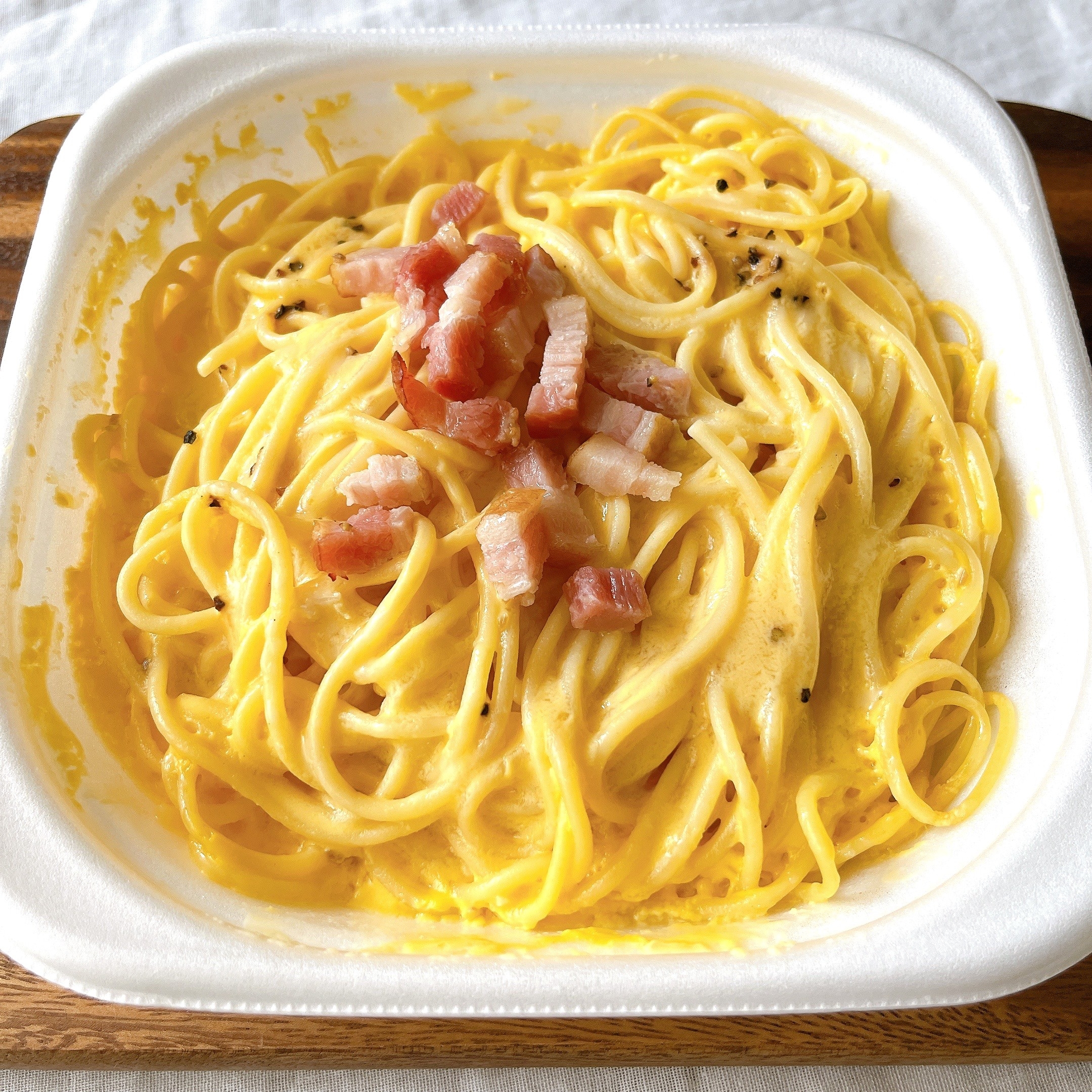 パスタ料理のクローズアップ、クリーミーなソースにベーコンがトッピングされています。