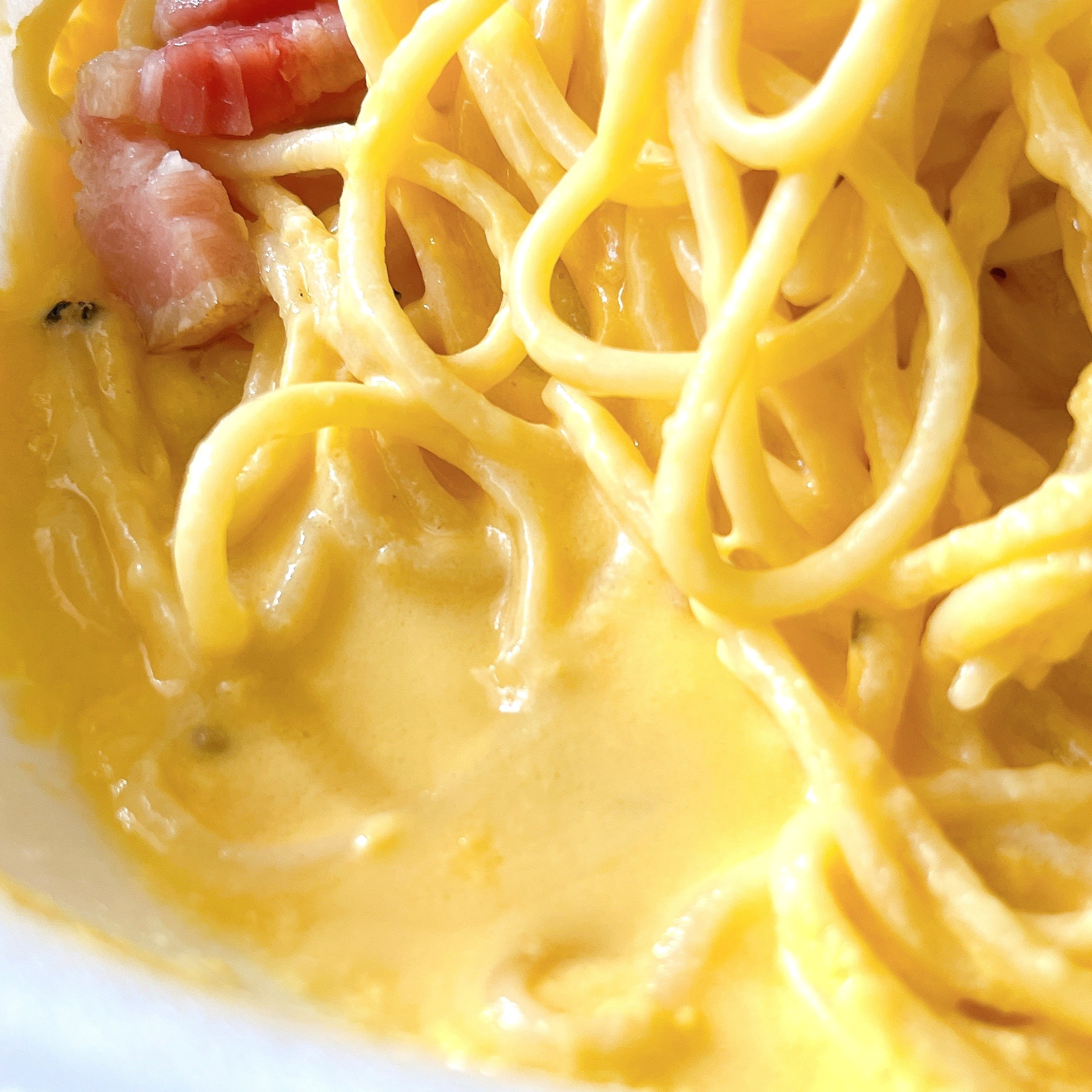 クリーミーなソースに絡めたスパゲッティ。バックにはベーコンの一部が見えます。