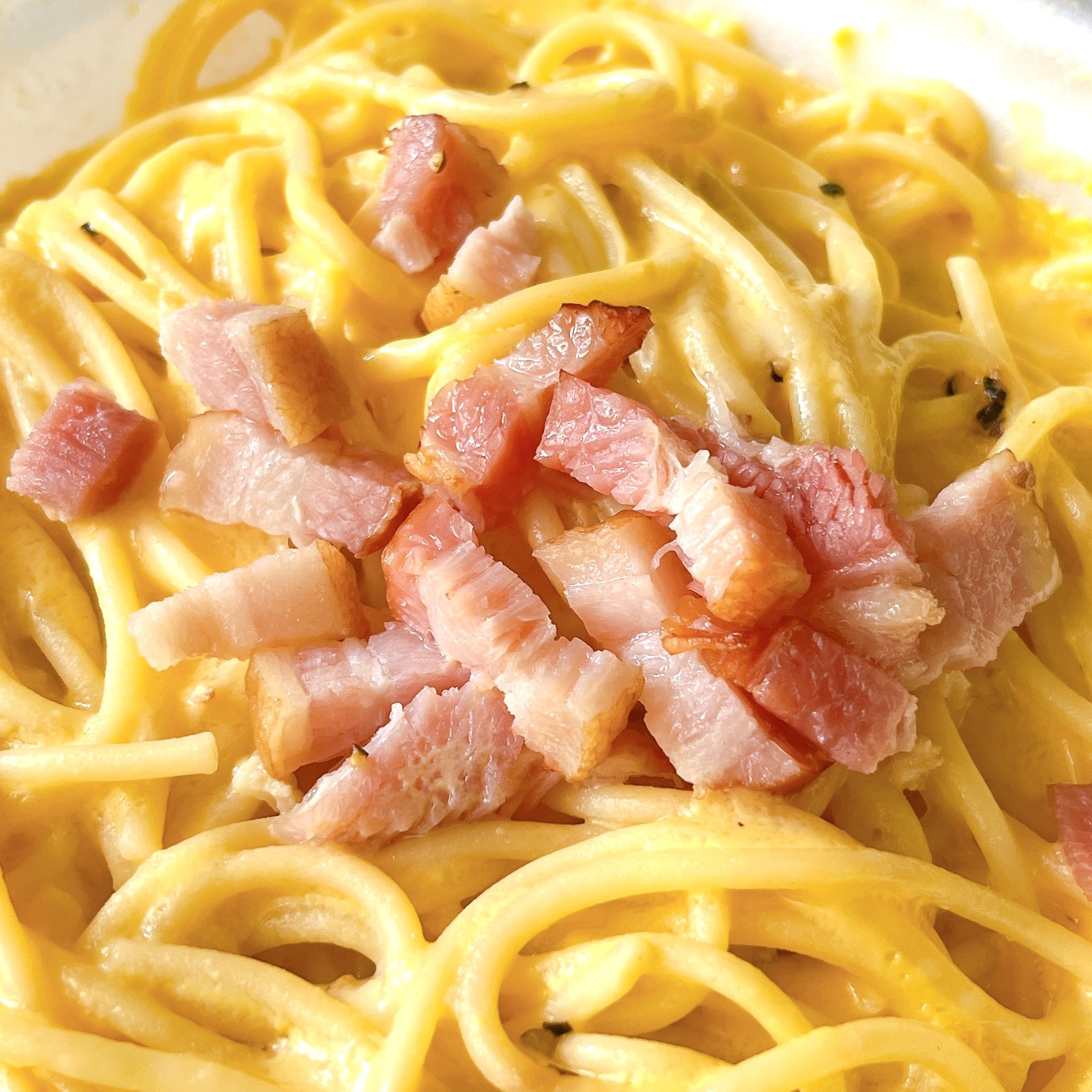 カルボナーラパスタの上に細かく切られたベーコンが乗っている。