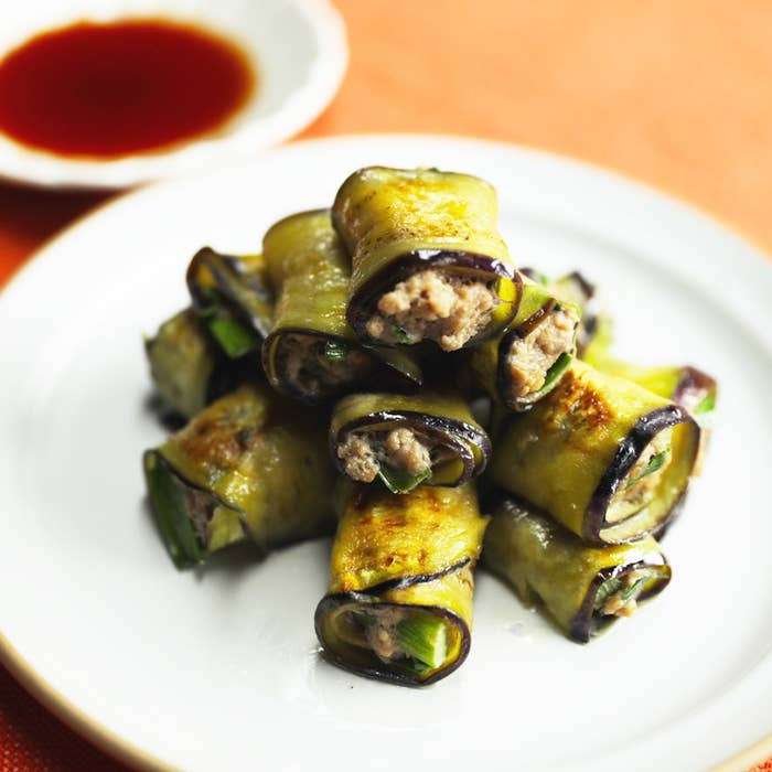 お皿に盛られたナスの巻物料理、フィリングは見えていないが、肉のようなものが詰められている。後ろには小皿のソース。