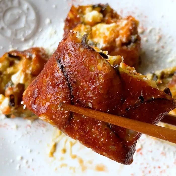 寿司の一種であるうなぎロールが箸で持ち上げられている。