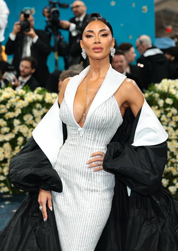 Nicole Scherzinger posing confidently on a formal event carpet surrounded by photographers