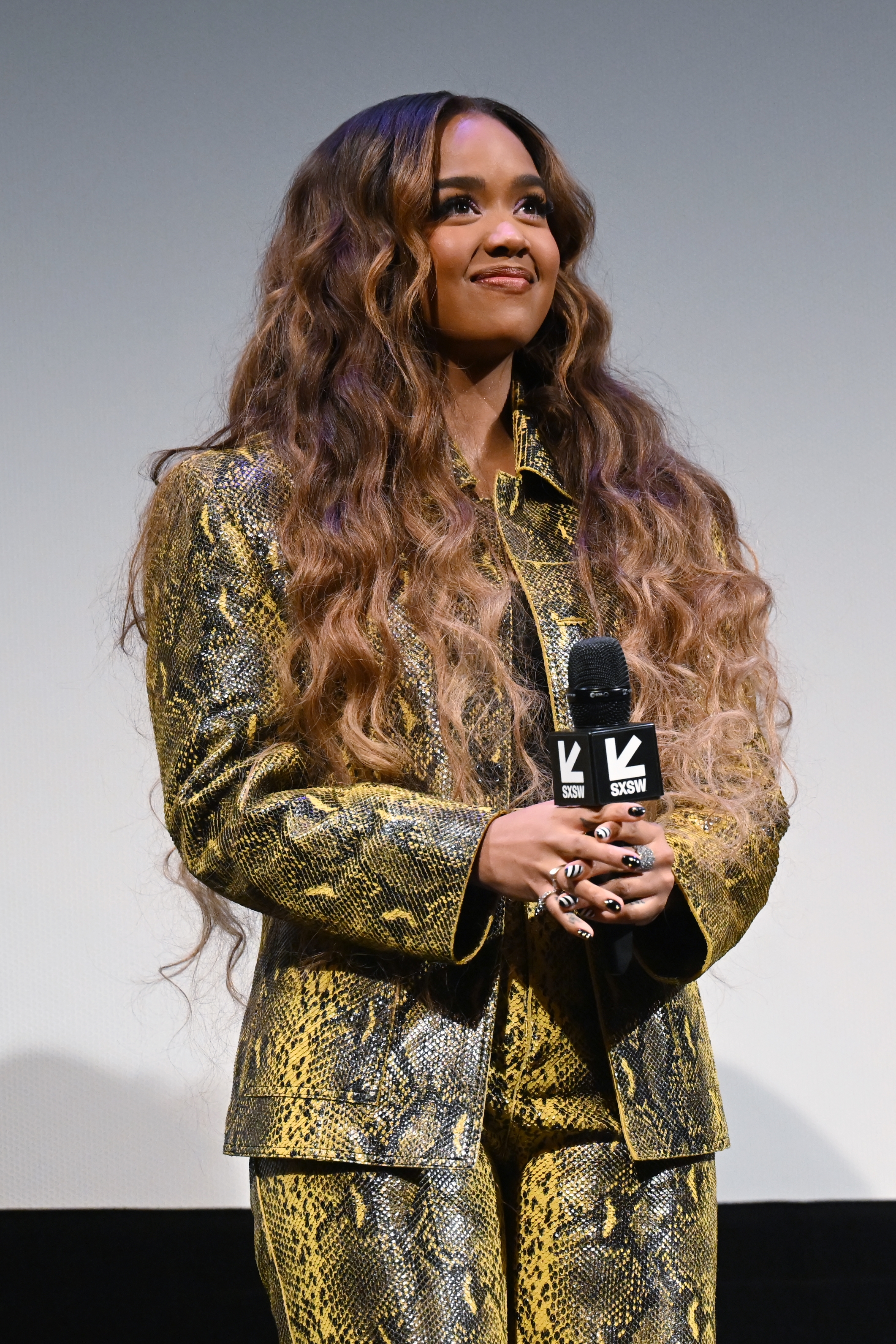 H.E.R. on stage, holding a microphone