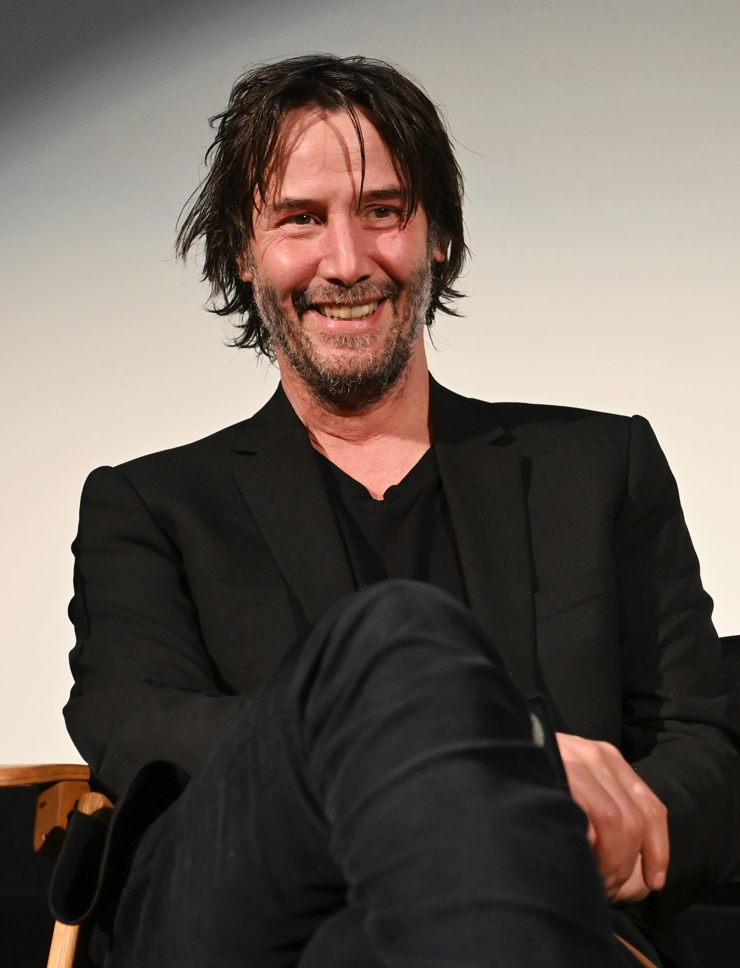 Keanu Reeves sitting and smiling