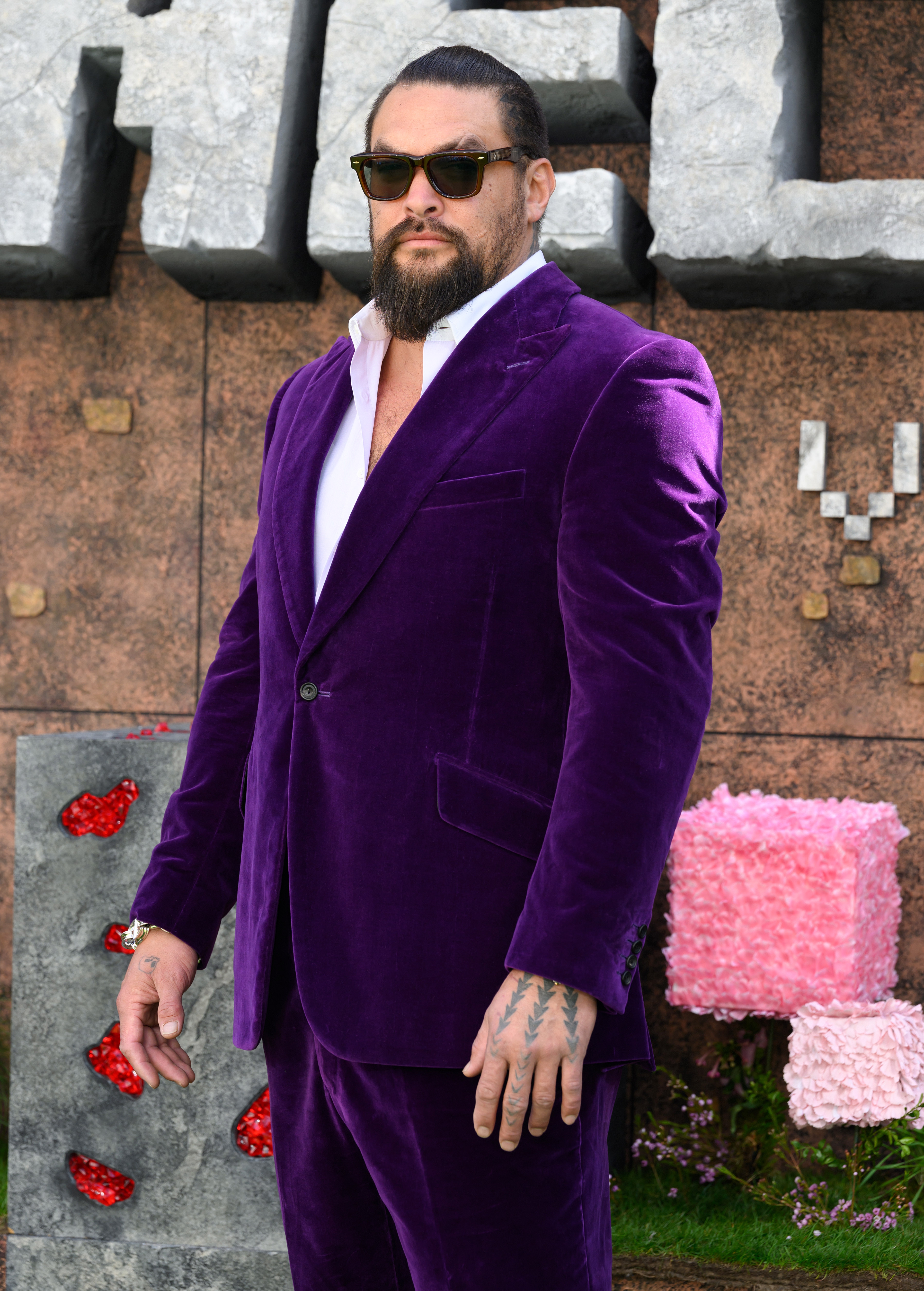 Jason Momoa in a stylish velvet suit with sunglasses on a red carpet
