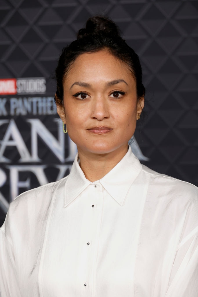 Person on red carpet wearing a white, button-up blouse with minimalistic style, attending a "Black Panther: Wakanda Forever" event