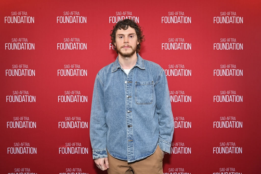 Evan Peters in casual denim shirt and khaki pants stands in front of a SAG-AFTRA Foundation backdrop
