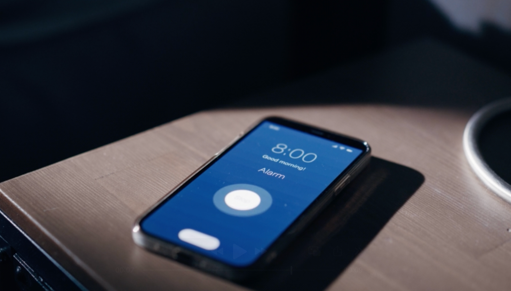 Smartphone on nightstand showing 8:00 alarm screen, partially illuminated
