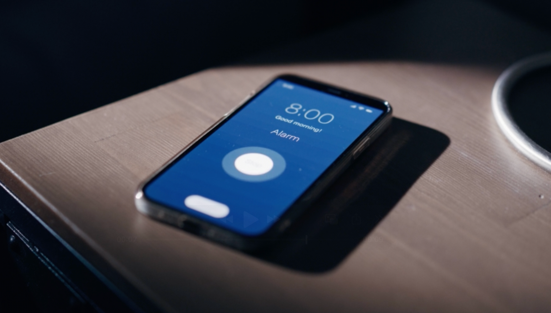 Smartphone on nightstand showing 8:00 alarm screen, partially illuminated