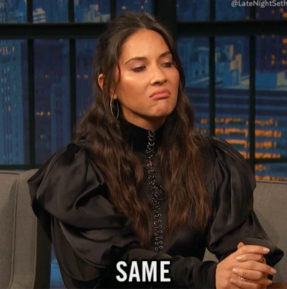 A person on a talk show set wearing a stylish black dress with puffed sleeves, displaying a smirk. Text at the bottom reads "SAME."