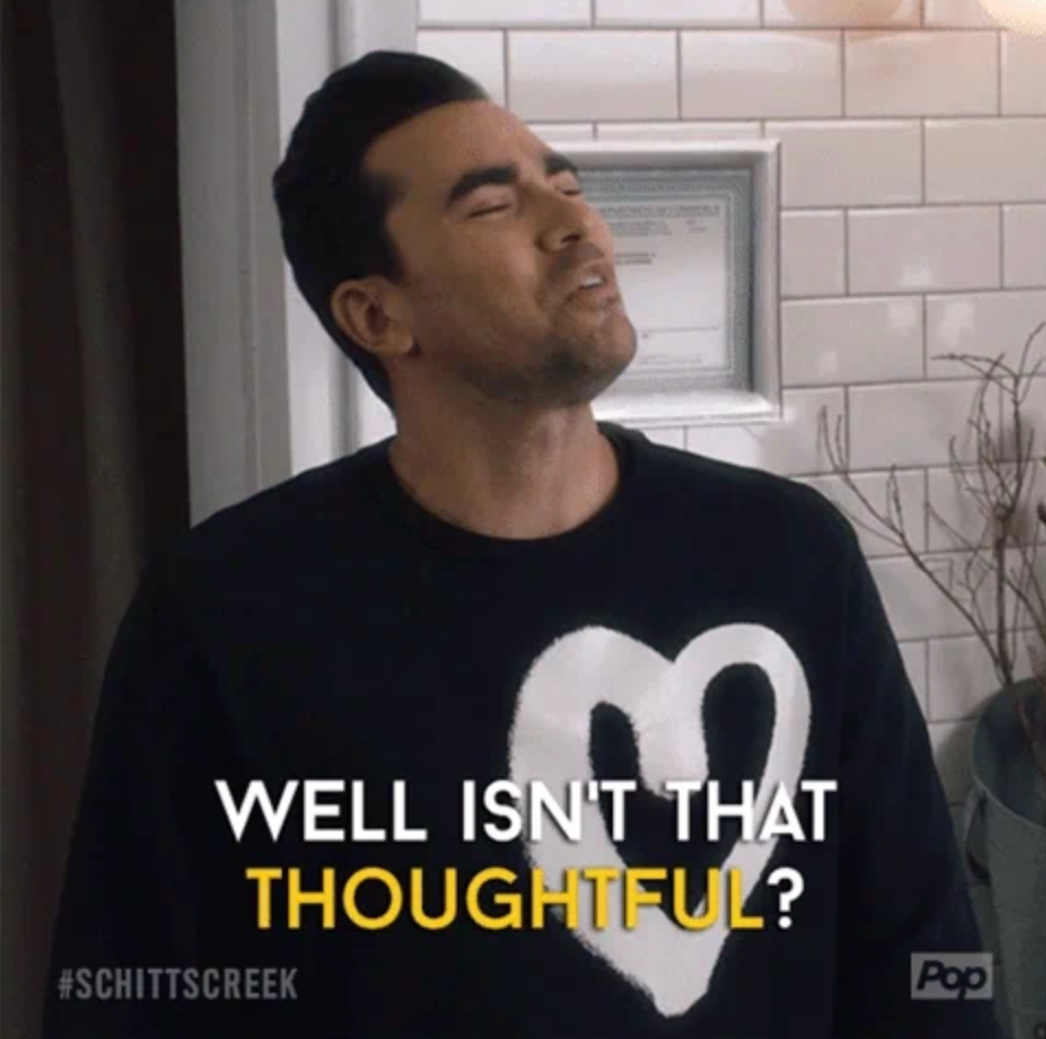 A person with short hair and a beard is wearing a heart sweater, looking up with a thoughtful expression. Text reads: "Well isn't that thoughtful?"