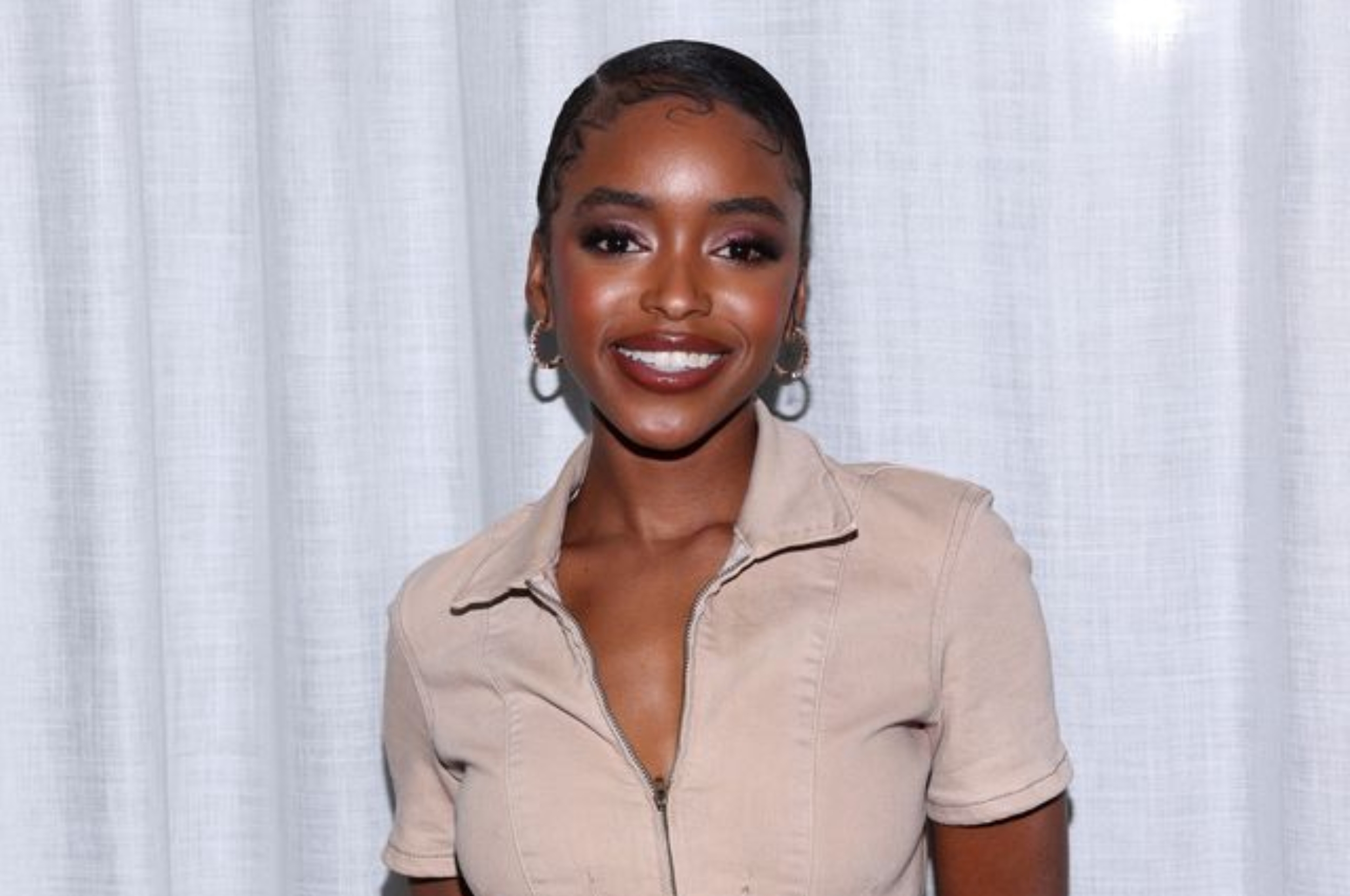 Person in a casual short-sleeve outfit, smiling against a plain backdrop